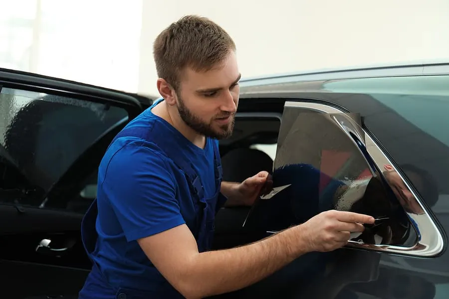 Installer trimming window film on a rear quarter window